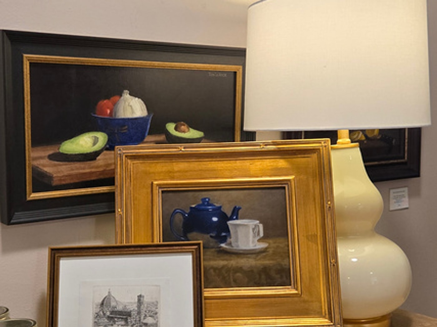 The new design table in the Langley Art & Home studio, styled with framed paintings and a lamp