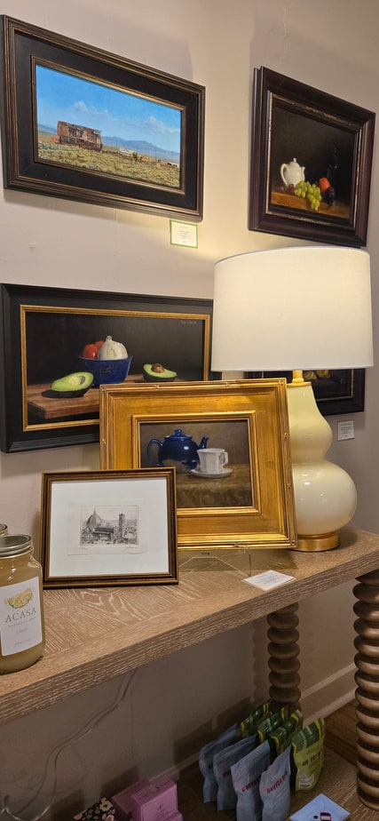 The new design table in the studio, styled with framed paintings and a lamp.